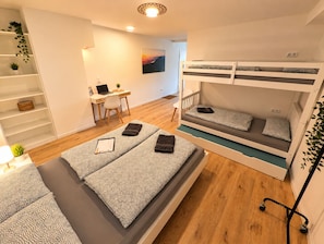A room with a bunk bed, a desk with a laptop, a chair, a shelf with plants, and a view of the sunset. - Modern Apartment with Stunning Mountain Views @ Sunrise Pfronten (Pfronten)