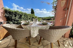 An outdoor dining area with wicker chairs and a table set for four. - Holiday apartment Le Petit Lézard (Cavalaire)