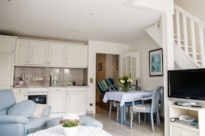 A compact living space with a kitchenette, a dining area, and a television. - Beach Villa Atlantic Apt. 2 (Norderney)
