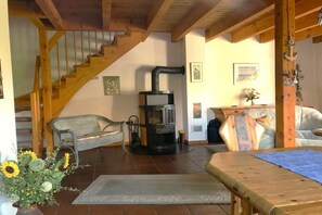 A cozy living room with a wooden staircase, a fireplace, and a dining area. - Holiday home with 2 bedrooms (Wangerland \/ Hooksiel)
