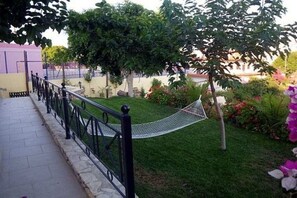 Ein Garten mit einer Hängematte, einem gepflasterten Weg und einem Zaun.