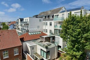 Un edifici d'apartaments modern amb múltiples balcons, grans finestres i una terrassa al terrat.