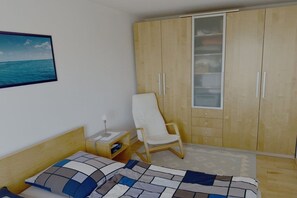 Ein Schlafzimmer mit Bett, Stuhl, Kleiderschrank und Nachttisch.