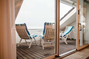 A balcony with two wooden chairs and a glass door. - Atlantic beach apartment (Norderney)