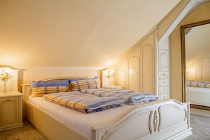 Quarto com cama, mesas de cabeceira, cômoda e um espelho grande.