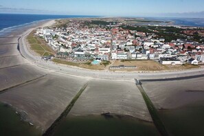 An aerial view of a coastal town with a beach, residential buildings, and a large open area. - Atlantic beach apartment (Norderney)