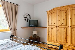 A bedroom with a bed, a television on a shelf, a wardrobe, and a window with curtains. - Country house Diemelsee (Diemelsee)