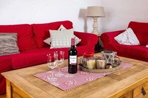 A red sofa with a wine bottle and glasses on a wooden table with a checkered tablecloth. - Country house Diemelsee (Diemelsee)