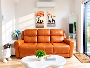 A modern living room with a leather sofa, a white coffee table, and artwork on the wall. - C 10 mins to Akl Airport/Brand New/6 Guest/Parking (Auckland)