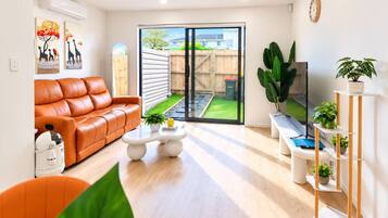 A modern living room with a leather sofa, a coffee table, and a TV on a wooden stand.