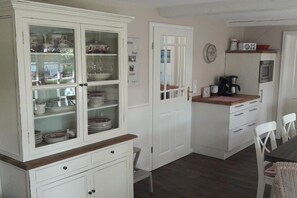 A kitchen with a white cabinet, a coffee maker, and a clock on the wall. - Holiday apartment with 1 bedroom (Borgsum)