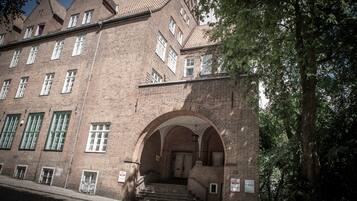 Ein großes Backsteingebäude mit zahlreichen Fenstern und einem zentralen Rundbogenportal.