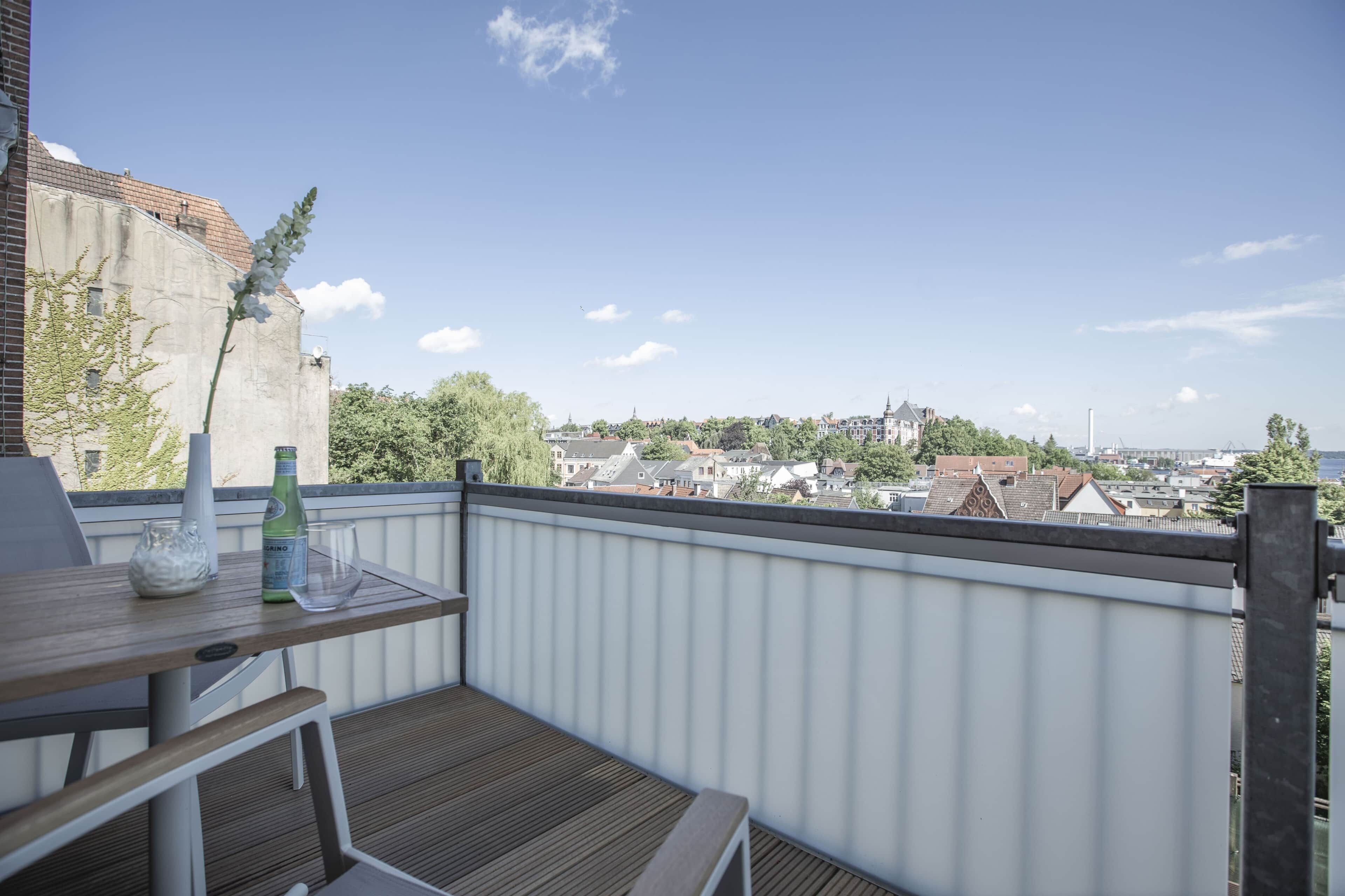 Un balcon avec une table, une bouteille et un verre.