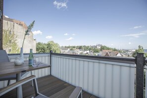 Ein Balkon mit Tisch, einer Flasche und einem Glas.