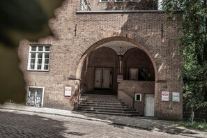 Ein Backsteinhaus mit einem zentralen Rundbogen und einer Treppe zum Eingang, mit einem Schild, das ein Pension angibt.
