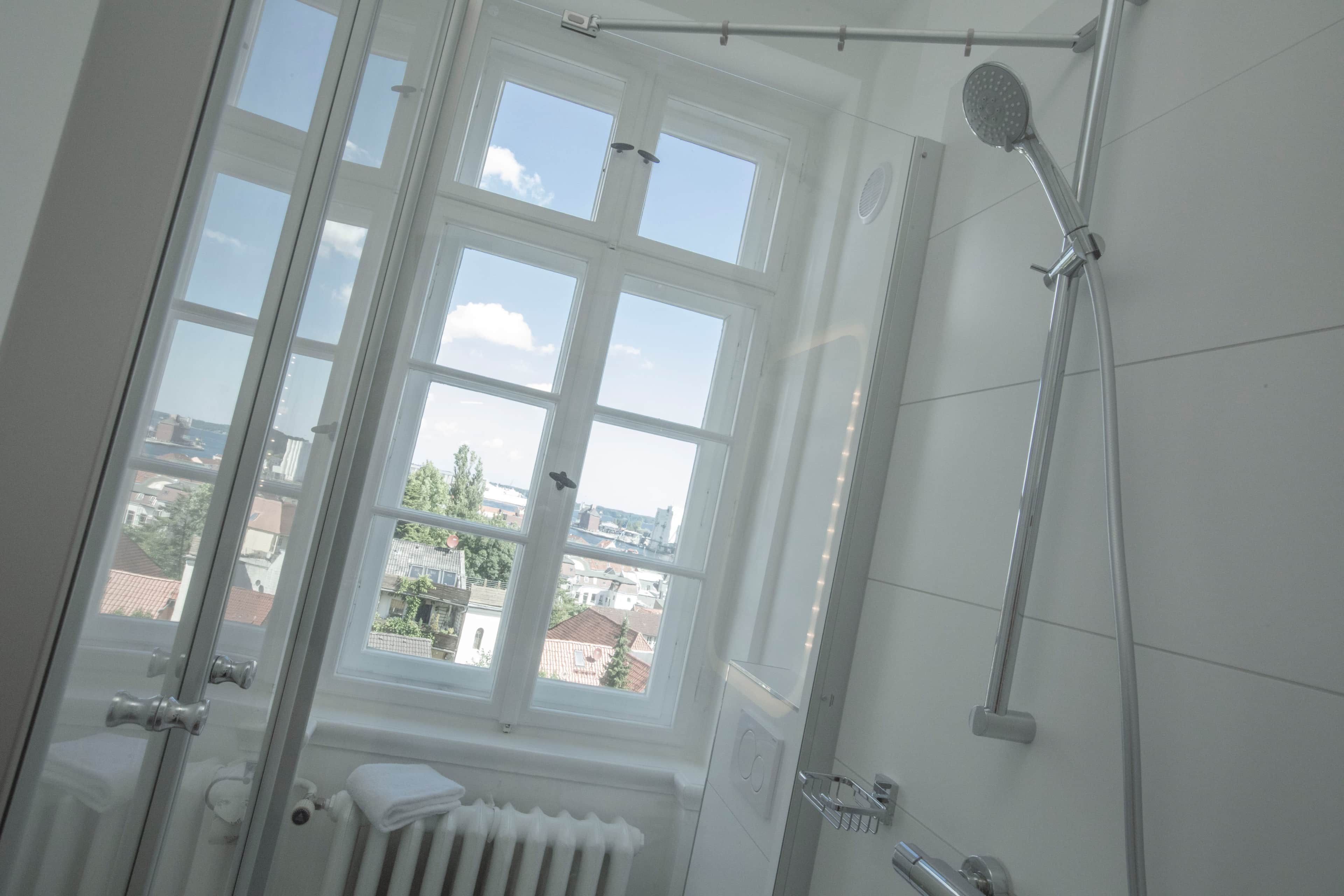 Une salle de bain avec une fenêtre, une douche et un radiateur.