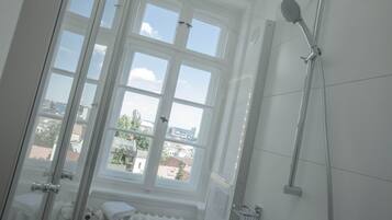 Une salle de bain avec une fenêtre, une douche et un radiateur.