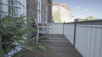 A balcony with a wooden floor, a white chair, and a table.