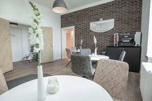 Un comedor moderno con pared de ladrillo, una mesa blanca y sillas tapizadas en gris.