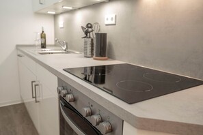 Una cocina moderna con estufa, horno integrados y una botella de vino en la encimera.