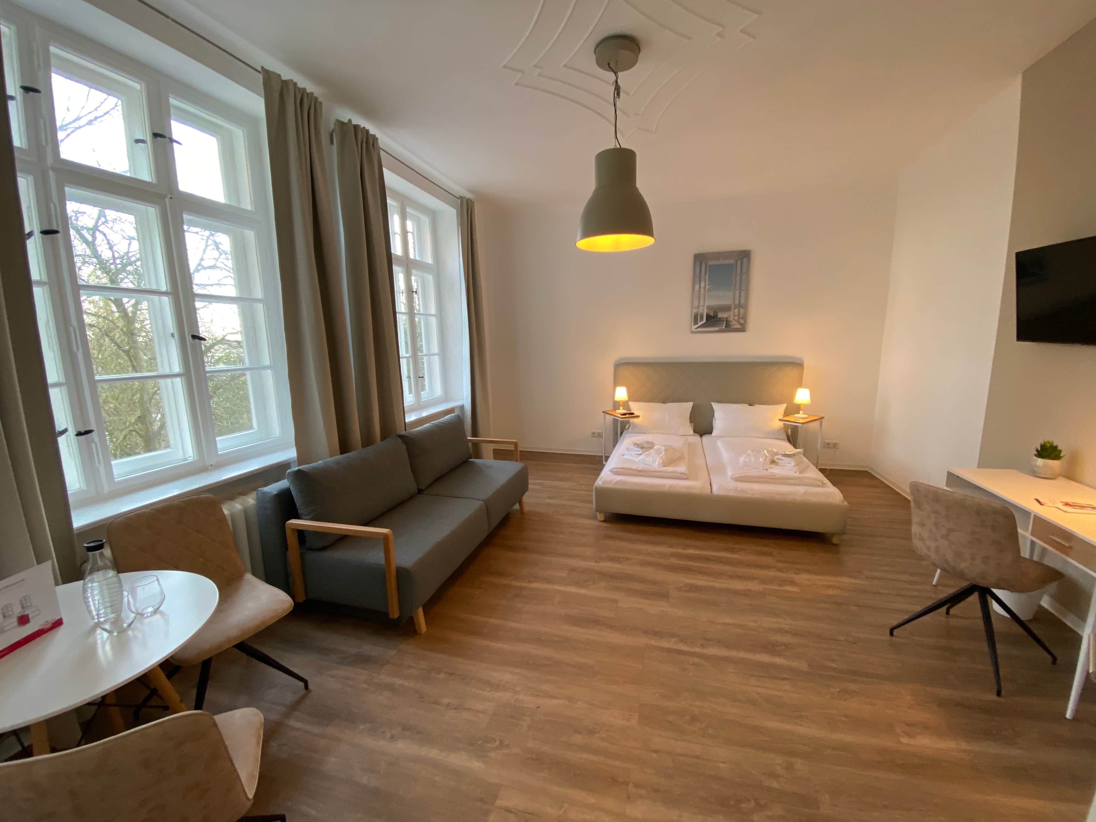 Ein Hotelzimmer mit einem Bett, einer Couch, einem Esstisch und einem Fernseher.