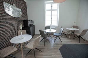 Ein modernes Interieur mit einer Ziegelwand, einer Kaffeemaschine und mehreren runden Tischen mit Stühlen.