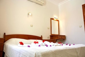 Ein Hotelzimmer mit Bett, Nachttisch, Spiegel und Klimaanlage.
