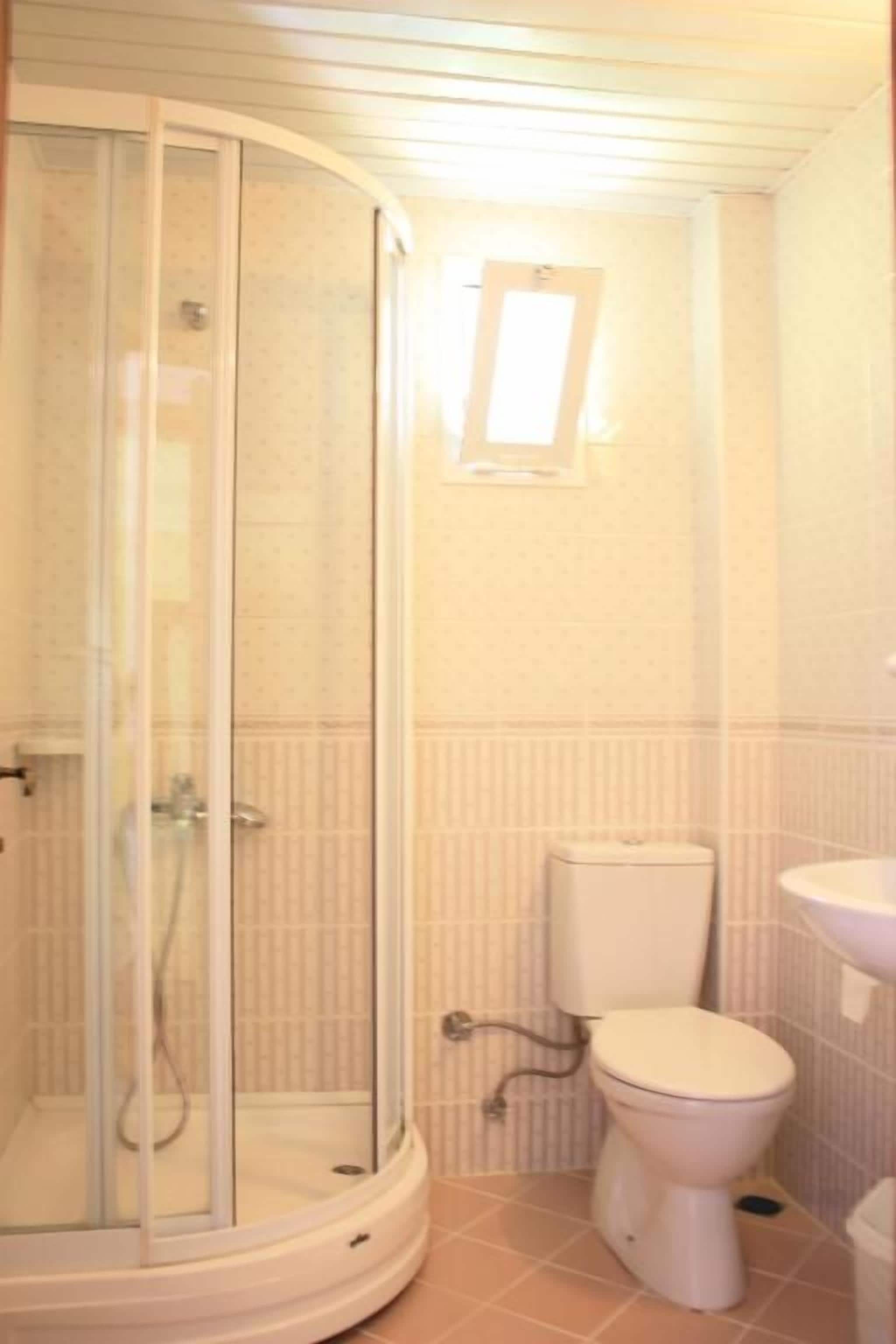 Un baño con cabina de ducha de vidrio, inodoro y lavamanos.
