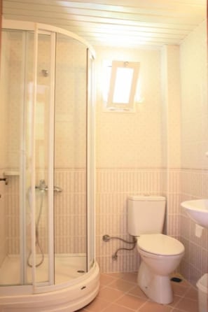Ein Badezimmer mit Duschkabine aus Glas, Toilette und Waschbecken.