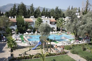 Ein Resort mit Swimmingpool, Liegestühlen und einem Spielplatz.