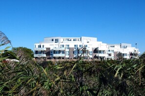 A modern multi-story building with a flat roof, large windows, and a uniform facade. - DEICHKIND de Baab in the Vitamar holiday park (Wurster Nordseeküste)
