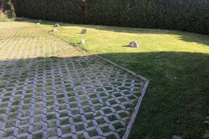 A paved area with a geometric pattern, surrounded by grass and a hedge. - Anchor in House Fördeglück (Glücksburg)