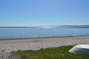A beach with a clear sky, calm water, and a grassy area with a white object. - Anchor in House Fördeglück (Glücksburg)