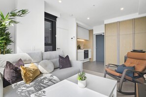 Una sala moderna con un sofá, una mesa de centro y una zona de comedor con una silla.