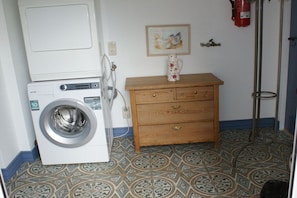 Ein Waschraum mit Waschmaschine, Holzschrank und gemusterten Bodenfliesen.
