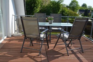 An outdoor deck with a glass-top table and four chairs. - Shell in House Fördeglück (Glücksburg)