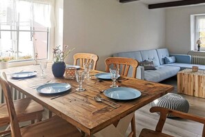 A dining area with a wooden table set for four, surrounded by wooden chairs. - Holiday apartment with 3 bedrooms (Wittmund)