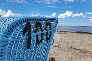 A beach chair with a woven pattern, a clear sky, and a calm sea in the background. - Holiday apartment with 3 bedrooms (Wittmund)