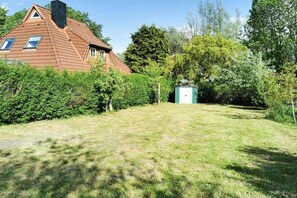 A house with a sloped roof, a small shed, and a well-maintained lawn. - Holiday apartment with 3 bedrooms (Wittmund)