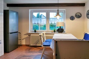 Une cuisine équipée d’un réfrigérateur, d’une fenêtre donnant sur un beau paysage, d’une chaise et d’une table.