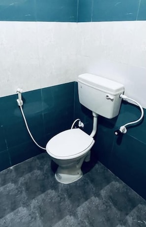 Un vàter amb dipòsit i seient blancs, connectat a una palanca de sortida fixada a la paret.