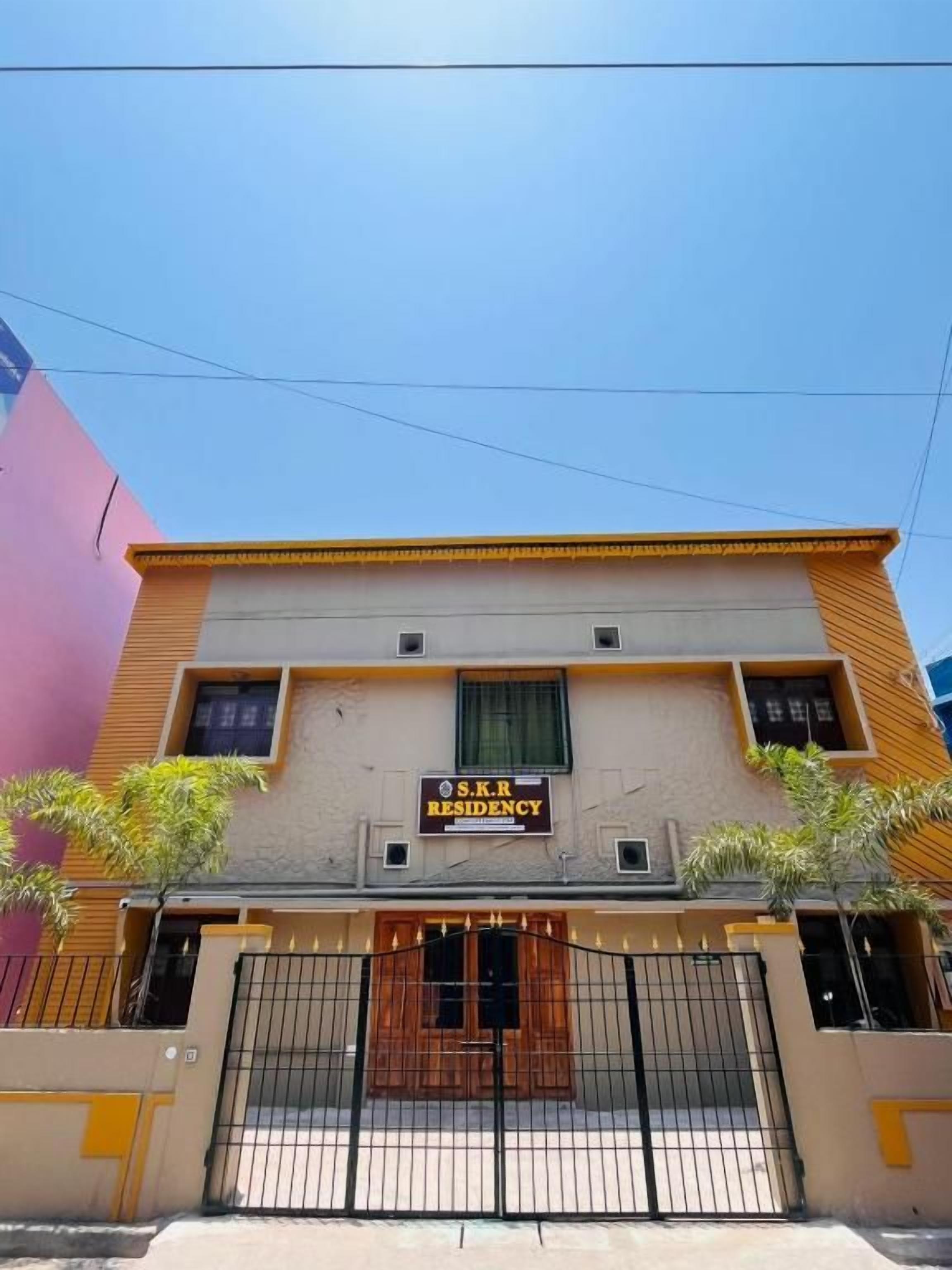 Un edificio de varios pisos con un letrero que dice 'S.K.R RESIDENCY'.