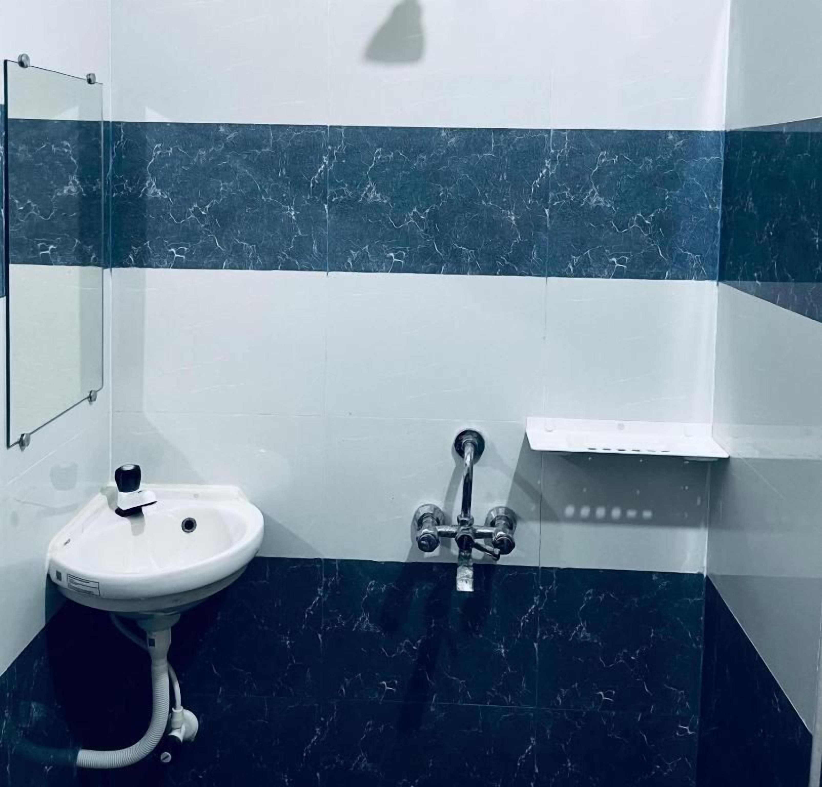 Un baño con lavamanos blanco, un espejo y zona de ducha.