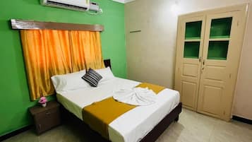 Una habitación de hotel con una cama, una mesita de noche, un aire acondicionado y un armario.
