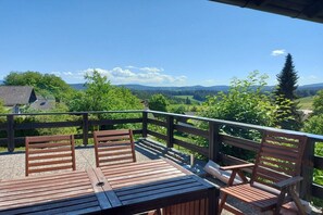 A wooden deck with two chairs and a table, overlooking a scenic landscape with hills and trees. - Holiday home in Zandt with swimming pool (Zandt)