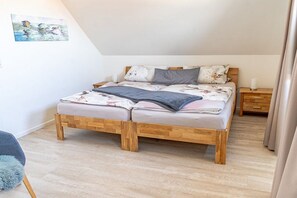 A bedroom with a wooden bed, a bedside table, a nightstand, and a painting on the wall. - Holiday home Sailing view Luv (Glücksburg)