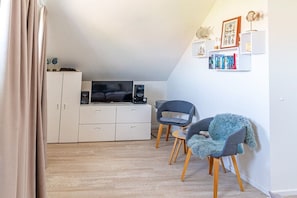 Ett kompakt bostadsutrymme med ett litet kök, en soffa, två stolar och en bokhylla.