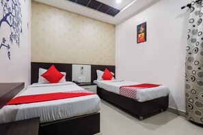 Habitación de hotel con dos camas, teléfono, toma de corriente y un cuadro en la pared.