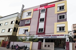 Un edificio de varios pisos con un letrero que dice 'Prabhakar's Hotel SSR Luxury' y 'Sai Santosh Residence Luxury Rooms'.