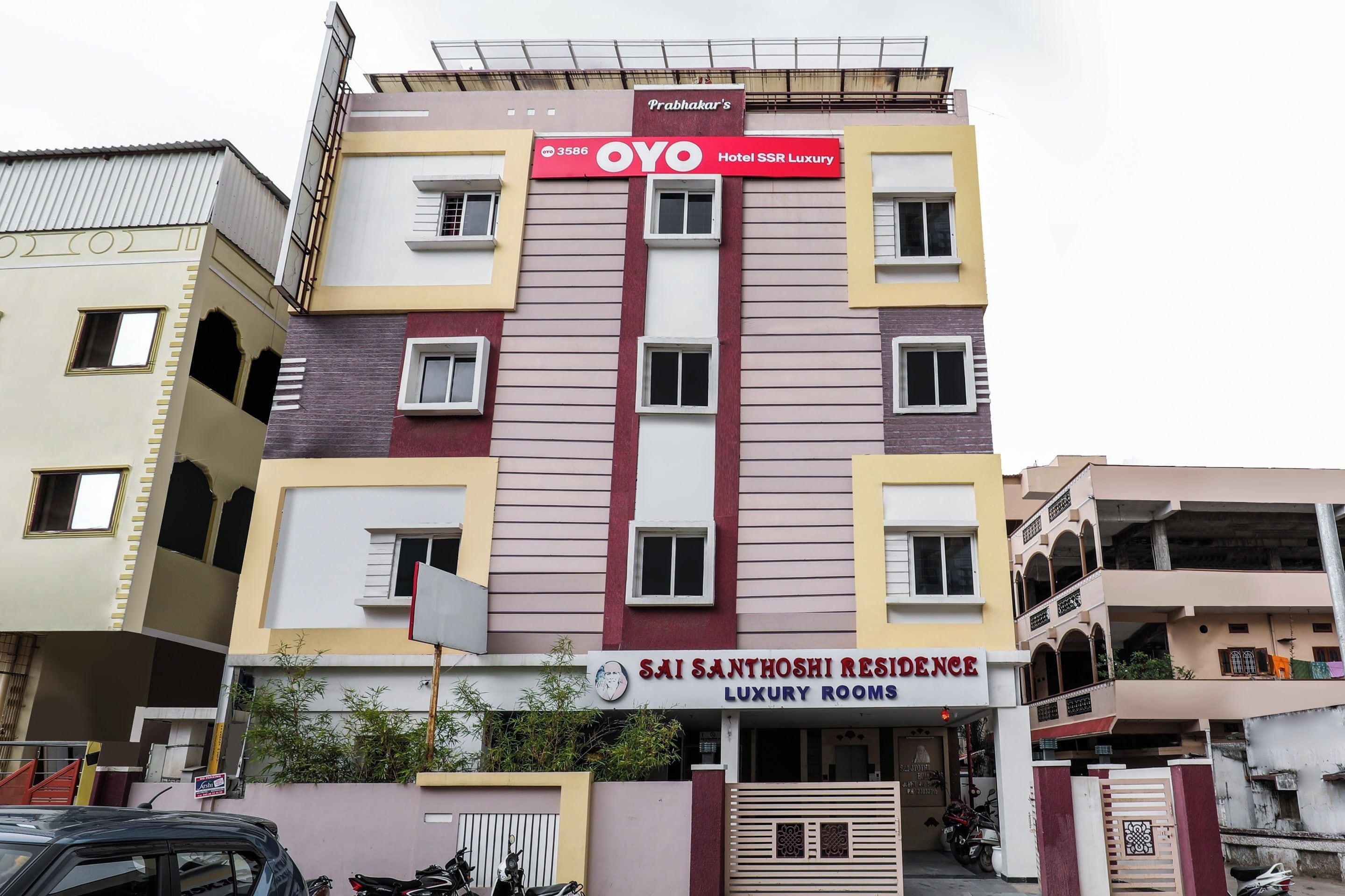 Um edifício de vários andares com uma placa grande nas cores vermelha e branca para OYO Hotel SSR Luxury.
